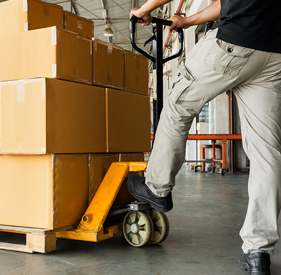 Warehouse operative moving palletised cargo with a pallet truck